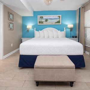 Cozy king suite featuring a plush bed, coastal decor, and a cozy seating area with a stylish ottoman
