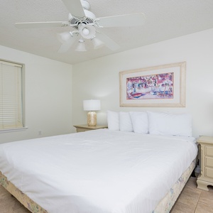 Guest bedroom featuring a queen bed with crisp white linens, decorative artwork, and warm bedside lamps