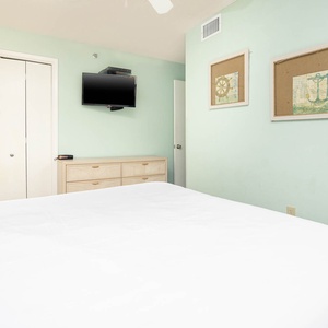 Relax in this inviting guest bedroom featuring a queen bed, soft decor, and a mounted TV