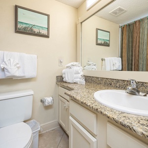 The guest bathroom features a granite countertop, elegant decor, and plush towels for a refreshing retreat