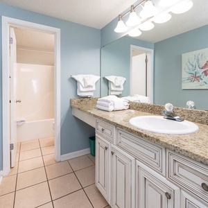 Refresh in the guest bathroom featuring a spacious granite countertop, soft towels, and beach-themed decor