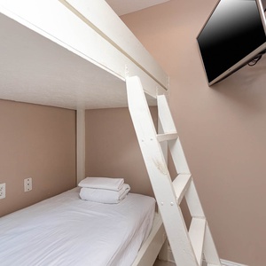This cozy bunk room features a bunk bed, fresh linens, and a wall-mounted TV for entertainment