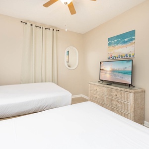 Relax in this cozy guest bedroom featuring two double beds, a TV, and beach decor for a comfortable stay