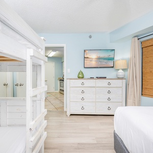 Inviting guest bedroom featuring a cozy twin bunk bed, full bed, dresser, and a wall-mounted TV for entertainment