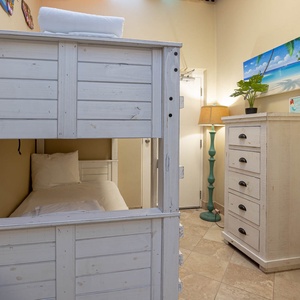 Cozy patio nook features two twin-over-twin bunk beds with wooden frame, complemented by a stylish dresser and warm lighting