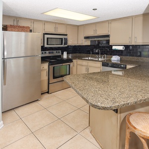 Prepare meals in the spacious kitchen featuring sleek appliances, ample counter space, and a cozy breakfast bar