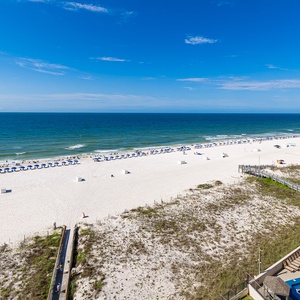 Beachfront view showcases white sand and vibrant umbrellas, perfect for a relaxing coastal getaway