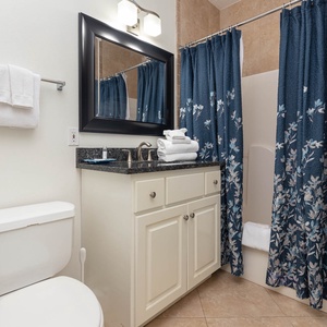 Additional full bathroom featuring a granite countertop, elegant navy floral shower curtain, and neatly stacked white towels