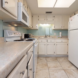 This kitchen features white cabinetry, a spacious countertop, and essential appliances, perfect for your culinary adventures