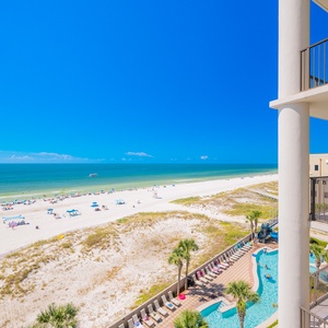 Breathtaking view of the pristine beach and turquoise waters from a spacious balcony with inviting lounge chairs