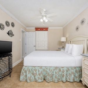 The guest bedroom features a queen bed with decorative bedding, a TV on a stylish stand, and soft lighting