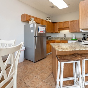 Prepare meals in this kitchen featuring granite countertops, stainless and white appliances, and inviting seating