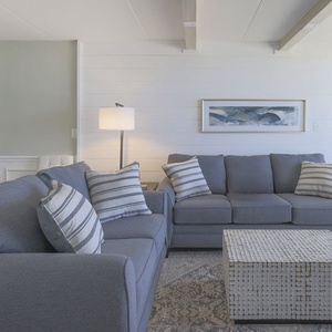 This inviting seating area features comfortable gray sofas, a stylish coffee table, and a bright view through large windows