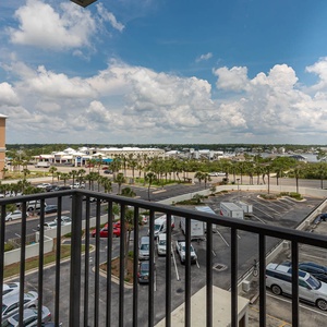 The master balcony view showcasing palm trees under a bright blue sky with fluffy clouds