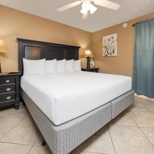 Brightly decorated bedroom featuring a large king bed with multiple pillows, stylish nightstands, and a TV for entertainment