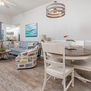 Living area features a cozy sofa with queen sleeper, dining table, and inviting decor, with a view of the beach