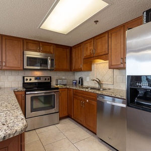 Warm wooden cabinets complement the granite countertops in this modern kitchen, featuring stainless appliances