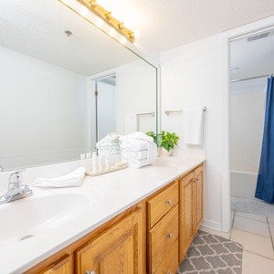 Master bathroom featuring a double sink vanity with wooden cabinetry, decorative accents, and a tub/shower combo