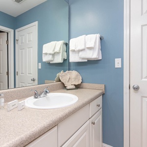 This bathroom features a light blue accent wall, a spacious countertop, and neatly arranged towels for a refreshing stay