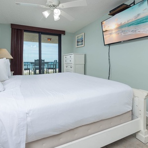 Comfortable master bedroom featuring a king bed, a TV, and beach balcony access