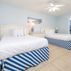 Relax in this inviting guest bedroom featuring two double beds, coastal decor, and soft blue walls