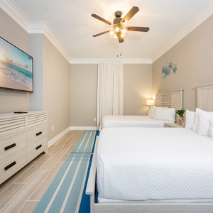 Relax in this inviting guest room featuring two queen beds, a large TV, and coastal decor for a refreshing stay