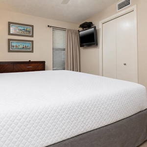 Cozy bedroom featuring a plush king bed, decorative artwork, and a wall-mounted TV for entertainment