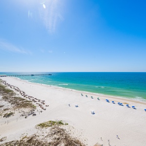 This serene beachfront view showcases soft white sand and gentle waves, perfect for a relaxing getaway