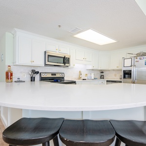 Gather around the spacious kitchen counter, perfect for casual meals and conversations in a bright kitchen