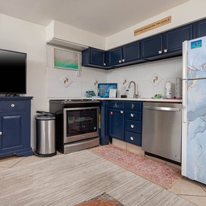 The kitchen features stylish blue cabinets, stainless appliances, and a TV, creating a space perfect cooking and entertaining