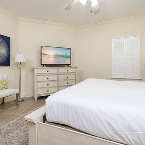Retreat to the tranquil master bedroom featuring a king bed, a TV, and a cozy chair for relaxation