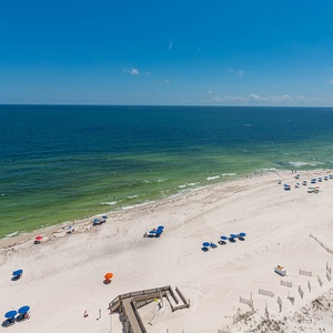 Gaze at the inviting shoreline with colorful umbrellas and soft sands, perfect for a day of relaxation and fun