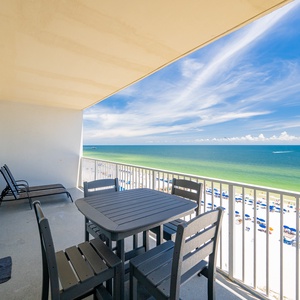 This balcony offers a stunning beachfront view with a dining table and lounge chairs for relaxing in the sun