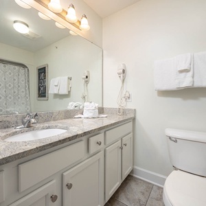 This guest bathroom features a sleek granite countertop, a spacious mirror, and fresh towels for a comfortable stay