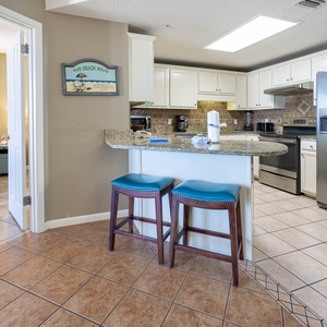 Gather around the breakfast bar with teal stools, enjoying easy access to the kitchen and a cozy master bedroom view