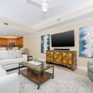 This living area features a large TV, stylish decor with blue and green accents, and a cozy seating arrangement