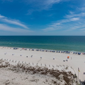 Enjoy the expansive view of the shoreline, with colorful umbrellas and beachgoers enjoying the sun and surf