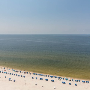 Walk barefoot along warm sand and listen to gentle waves while rows of blue umbrellas dot the beach