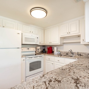 The kitchen features white cabinets, granite countertops, and modern appliances, perfect for preparing meals during your stay