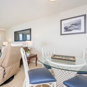 Living area features a glass dining table, comfortable seating, and decorative accents, creating a welcoming atmosphere