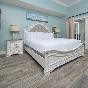 The serene master bedroom features a plush king bed, soft blue walls, and elegant decor, perfect for a restful getaway