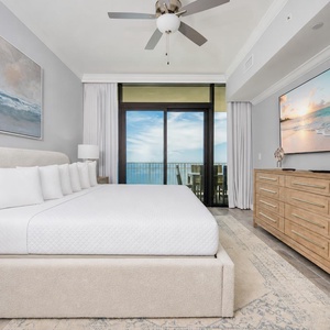 King master suite featuring a cozy bed with soft linens, large TV, and beachfront balcony access