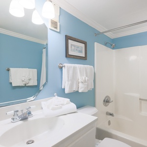 This bathroom features a bright blue wall, elegant fixtures, and fluffy towels, creating a refreshing and inviting space