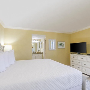 Brightly colored walls in the master suite complement the king bed, while a flat-screen TV and adjacent bath enhance the vibe
