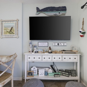 This cozy living area features a large TV, beach-themed decor, and a welcoming atmosphere perfect for relaxation