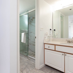 The master bath features a walk-in shower with a glass enclosure and a stylish vanity with a light granite countertop
