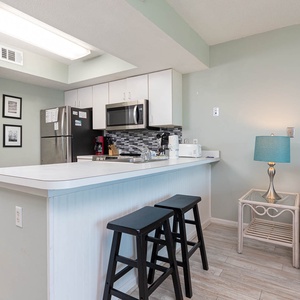 This kitchen features sleek stainless appliances, a stylish backsplash, and a cozy seating area for relaxed gatherings