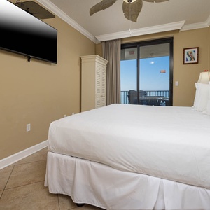 Relax in the comfortable master bedroom with a large king bed, a flat-screen TV, and a view of the beach