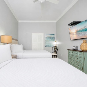 Rest comfortably in this inviting guest room featuring two queen beds, a stylish chair, and a TV