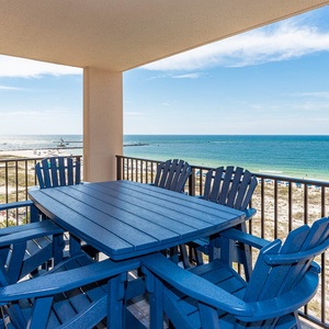 Gather around the blue outdoor table to enjoy meals with breathtaking views of the coastline and gentle waves